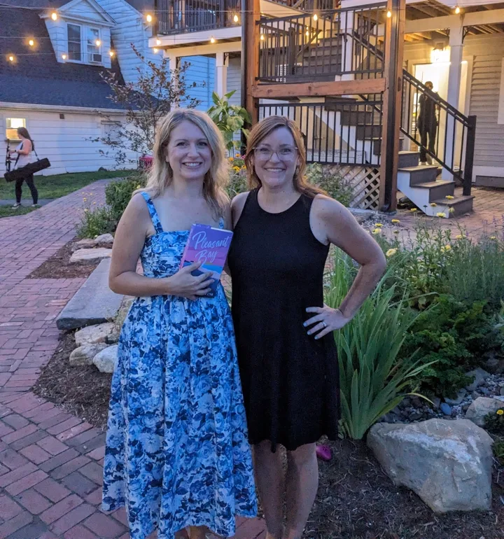 Toni Rocchetti at an outdoor book event with a friend at dusk